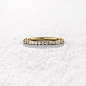 May include: A thin gold band with a row of small diamonds set in a pave setting.
