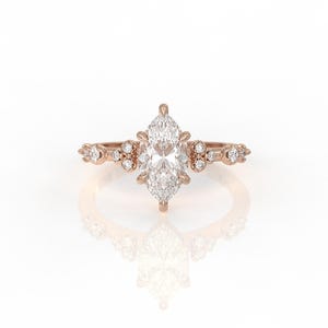 May include: A rose gold engagement ring featuring a marquise-shaped diamond centre stone and smaller diamonds set in the band.