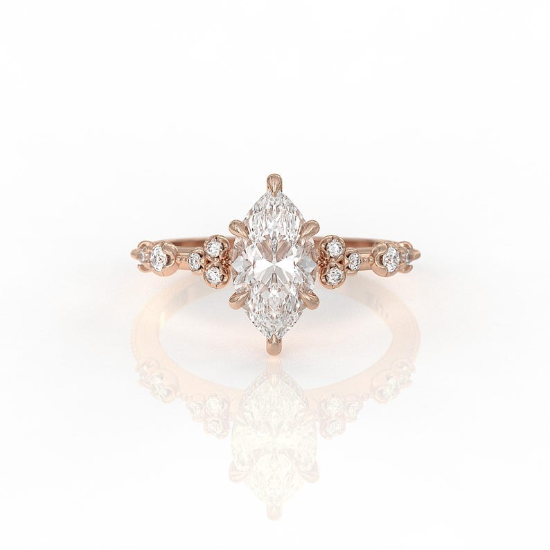 May include: A rose gold engagement ring featuring a marquise-shaped diamond centre stone and smaller diamonds set in the band.
