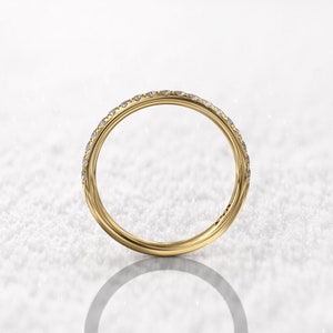 May include: A thin gold band with a row of small diamonds set in a pave setting.