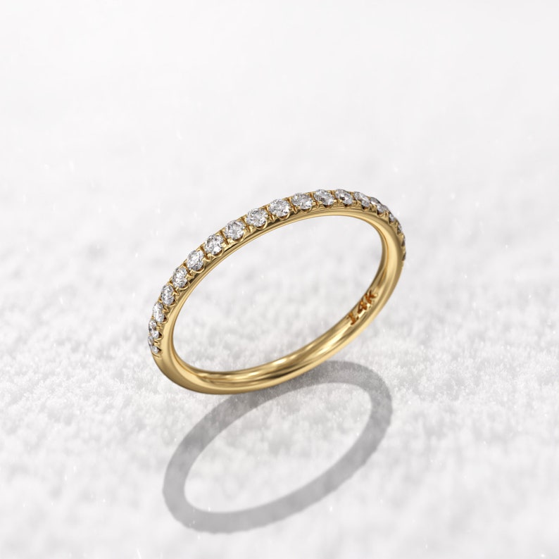 May include: A thin gold band with a row of small diamonds set around the entire ring.