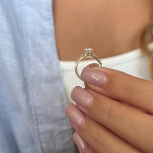 May include: A gold engagement ring with a single large diamond and smaller diamonds set in the band.