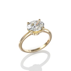 May include: A gold engagement ring with an oval-shaped diamond. The ring is set in a simple band and has a 14k stamp on the inside.