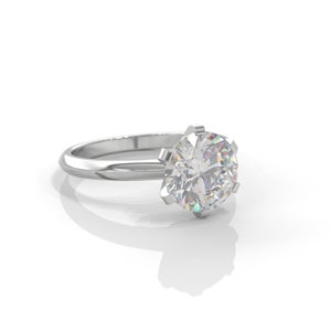 Pu&ograve; includere: Un anello di fidanzamento in argento con un grande diamante rotondo e trasparente.