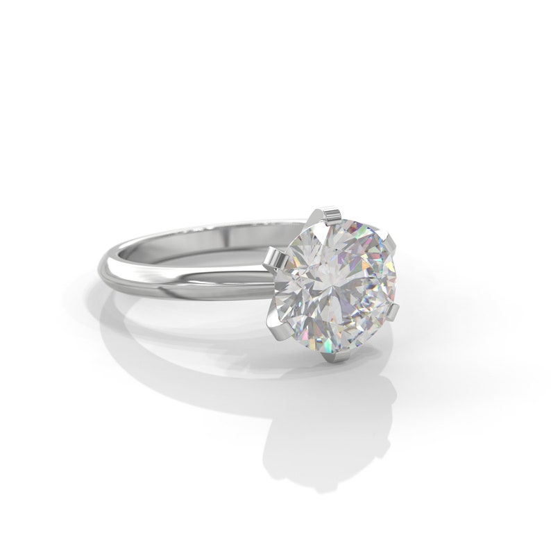 Pu&ograve; includere: Un anello di fidanzamento in argento con un grande diamante rotondo e trasparente.
