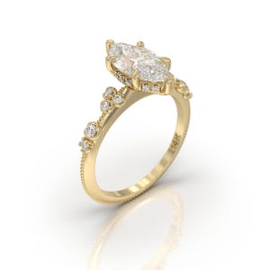 May include: A gold engagement ring featuring a marquise-shaped diamond centre stone and smaller diamonds set in the band. The band is adorned with small clusters of diamonds.
