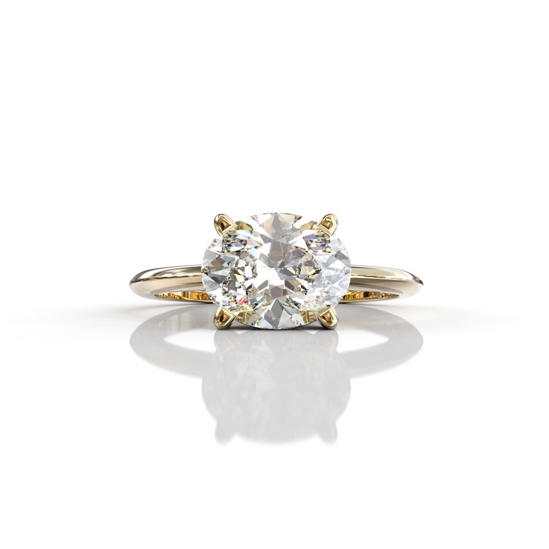 May include: A gold engagement ring with a large, clear oval-shaped diamond.