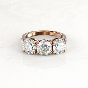 Front view of a two-tone three-stone moissanite engagement ring, with yellow gold prongs and inner settings, a white/silver-colored band, and a visible 14K stamp inside.