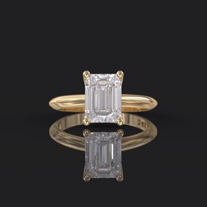 Pu&ograve; includere: Un anello di fidanzamento in oro con un grande diamante a taglio smeraldo trasparente.