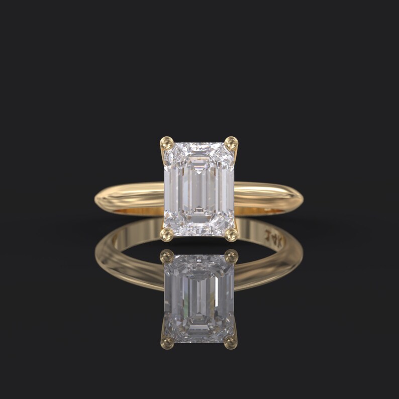 Pu&ograve; includere: Un anello di fidanzamento in oro con un grande diamante a taglio smeraldo trasparente.