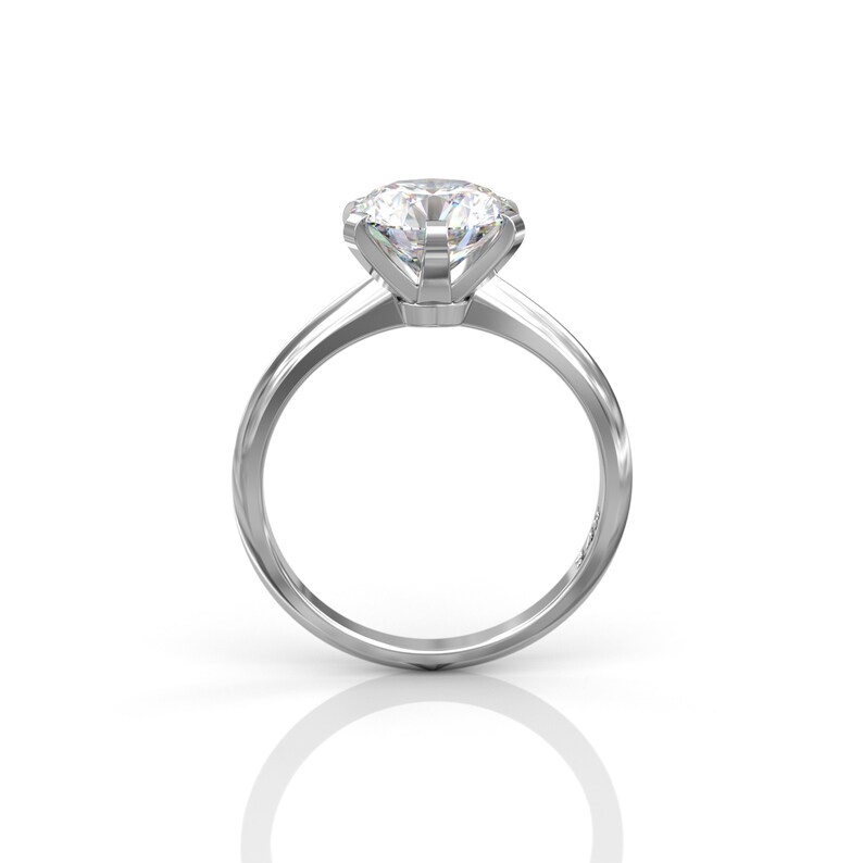 Pu&ograve; includere: Un anello di fidanzamento solitario in argento con un grande diamante rotondo e trasparente.