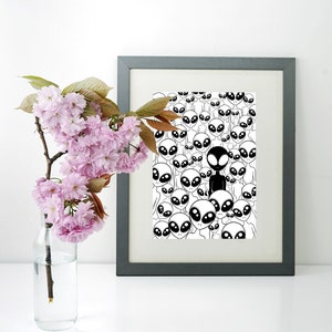 May include: A black and white framed print of a pattern of aliens with one alien in black standing out from the rest.