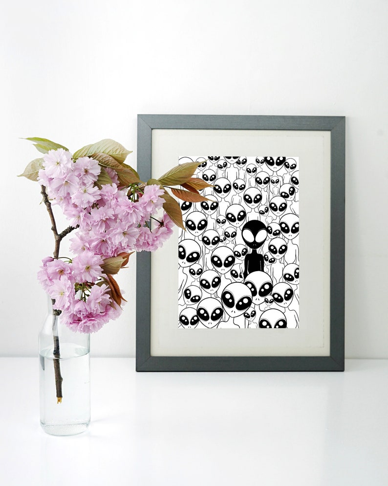 May include: A black and white framed print of a pattern of aliens with one alien in black standing out from the rest.