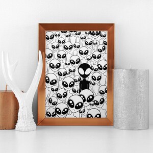 May include: A framed print with a black and white illustration of a crowd of aliens. One alien is black, while the rest are white. The frame is copper colored.