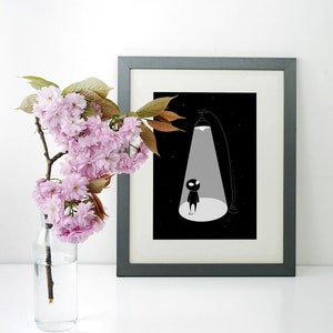 May include: A black and white illustration of a small figure standing in a spotlight. The figure is silhouetted against a black background with white stars. The illustration is framed in a grey frame.