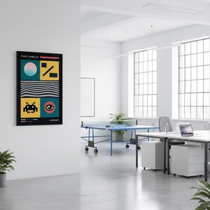 Puede incluir: Un estampado artístico enmarcado con borde negro cuelga de una pared blanca. La obra presenta formas geométricas, un personaje de videojuego retro y el texto "TWO TWELVE" y "POSTERART". La paleta de colores incluye turquesa, amarillo, negro y rosa.