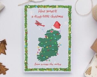 May include: Christmas card featuring a green map of Ireland decorated with Christmas lights and a Santa hat. The card has the text "Have yourself a derry little Christmas" and "from across the miles". A red airplane flies above the map.