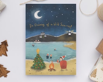 May include: A Christmas card with a whimsical illustration of a beach scene at night. The card features a Christmas tree, a bonfire, and people swimming in the ocean. The text on the card reads, "I'm Dreaming of a Wild Swim-mas!"
