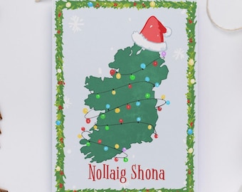 May include: A Christmas card featuring a green map of Ireland decorated as a Christmas tree with colorful lights and a Santa hat. The card has a green border with holly and the text "Nollaig Shona" in red.