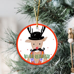 May include: Round Christmas ornament with a red border. A cartoon reindeer wearing a black top hat and a mustache with the text "No Sur-Reindeer!"