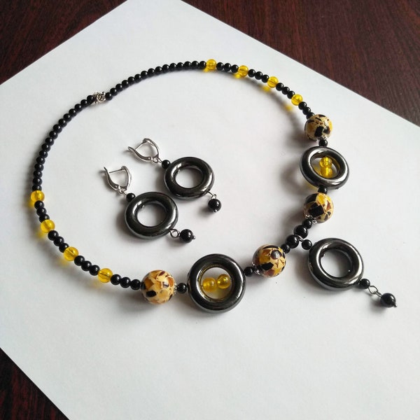 Parure de bijoux bohème avec perles acryliques. Boucles d'oreilles et pendentif avec perles jaunes et noires. Tour de cou avec fil à mémoire de forme. Fermoirs argentés.