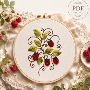 Può includere: Un telaio da ricamo rotondo con un design dettagliato di lamponi. Il ricamo presenta bacche rosse, foglie verdi e steli marroni, tutti cuciti su un tessuto color crema. Il testo "PDF DIGITAL" è visibile. Il diametro è di circa 20 cm.