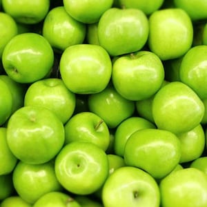 Könnte beinhalten: Eine Nahaufnahme eines großen Topfes voller leuchtend grüner Äpfel. Die Äpfel sind in einem zufälligen Muster angeordnet, wobei sich einige überlappen.