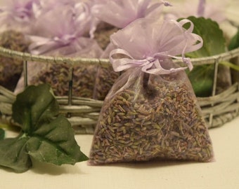 May include: A group of lavender-scented sachets in purple mesh bags with white ribbons. The sachets are filled with dried lavender flowers and are arranged in a wire basket.