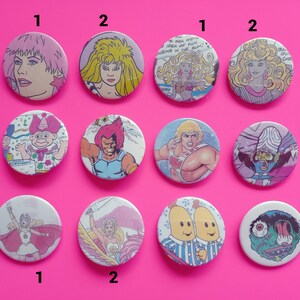 May include: A set of 10 round button pins featuring various cartoon characters. The pins are colorful and feature characters from popular cartoons and comics. The pins are numbered 1 and 2.