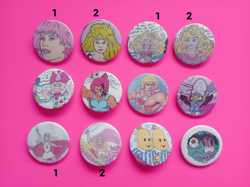 May include: A set of 10 round button pins featuring various cartoon characters. The pins are colorful and feature characters from popular cartoons and comics. The pins are numbered 1 and 2.