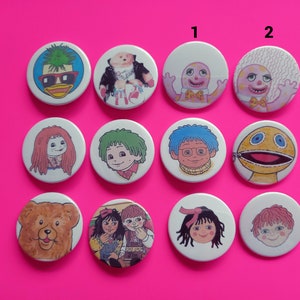 May include: Ten round white buttons with colorful cartoon images. The buttons feature characters from the children's television show, The Wombles. The buttons are arranged in two rows of five. The top row has the numbers 1 and 2 printed above the buttons.