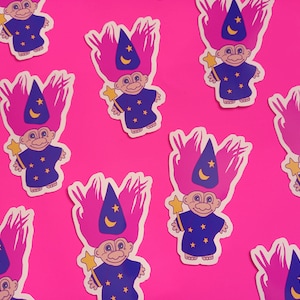 May include: Nine pink and purple troll stickers with blue wizard hats and stars. Each troll is holding a wand with a star on the end.