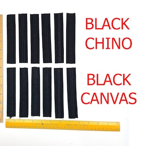May include: Black fabric strips labelled "BLACK CHINO" and "BLACK CANVAS" are arranged on a white surface. Two rulers, one marked in inches, are placed alongside the strips. The strips appear to be approximately 2.5 cm wide.