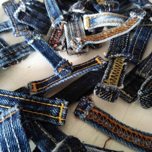 May include: A pile of blue denim fabric scraps with yellow stitching. The fabric scraps are various sizes and shapes.