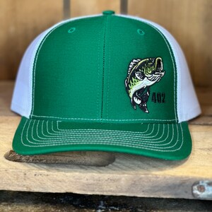 May include: A green and white trucker hat with a black and green bass fish graphic and the number 402 embroidered on the front.