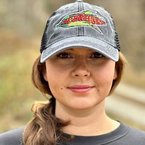 May include: A black and grey baseball cap with a mesh back. The cap has an embroidered corn cob with the word "Nebraska" on it.