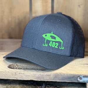 May include: A black and green trucker hat with a fishing lure logo and the number 402 embroidered on the front.
