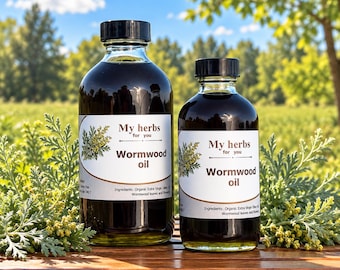 May include: Two clear glass bottles filled with dark wormwood oil, each featuring a white label with the text My herbs for you Wormwood oil and ingredients listed. The bottles have black screw caps and are surrounded by green wormwood plants.