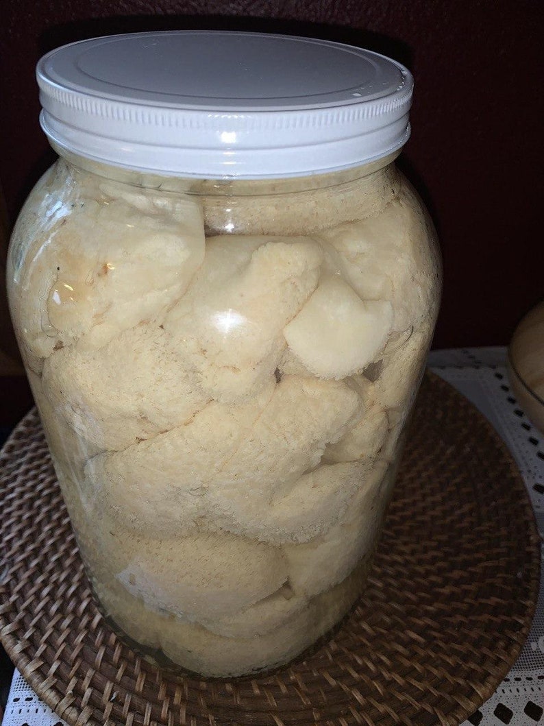 May include: A glass jar filled with white, irregularly shaped pieces of food. The jar has a white lid and is sitting on a woven brown placemat.