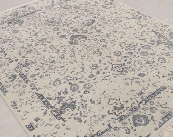 May include: A cream-colored rug with a gray floral pattern and a fringe border.