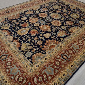 May include: A navy blue rug with a floral pattern in shades of red, gold, and cream. The rug has a border with a repeating pattern of flowers and leaves.