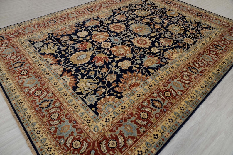 May include: A navy blue rug with a floral pattern in shades of red, gold, and cream. The rug has a border with a repeating pattern of flowers and leaves.