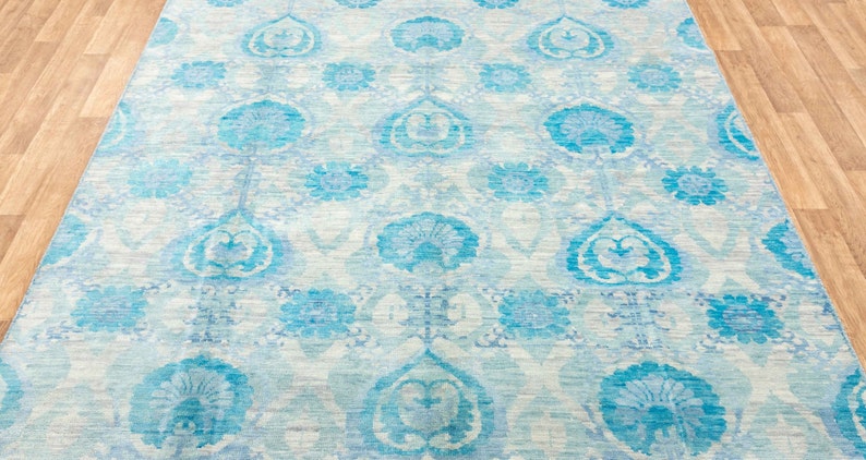 Puede incluir: Una alfombra azul claro con fondo blanco y un patr&oacute;n floral. La alfombra tiene un dise&ntilde;o tradicional con detalles intrincados.