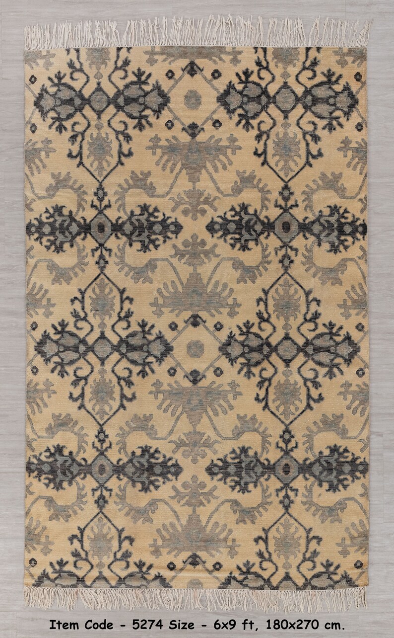 Puede incluir: Una alfombra beige con un patr&oacute;n geom&eacute;trico negro y gris. La alfombra tiene un borde de flecos y mide 6x9 pies o 180x270 cent&iacute;metros. C&oacute;digo de art&iacute;culo - 5274