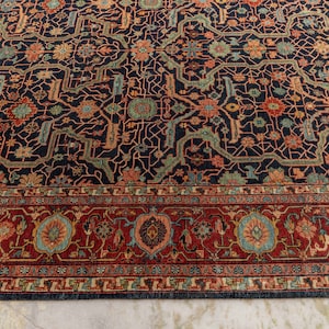 May include: A dark blue rug with a intricate floral pattern and a red border. The rug has a traditional Persian design.