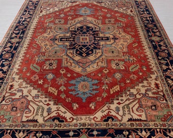 May include: A traditional Persian rug with a red background and intricate floral patterns in shades of blue, beige, and green. The rug has a dark blue border with a geometric design.