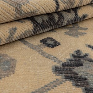 Puede incluir: Primer plano de una alfombra beige con un patr&oacute;n geom&eacute;trico gris oscuro y azul. La alfombra tiene una textura suave y mullida.