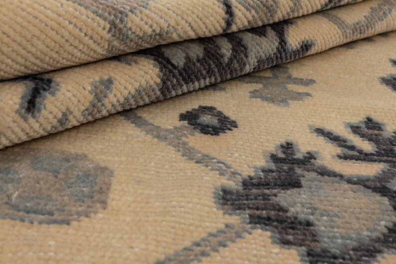 Puede incluir: Primer plano de una alfombra beige con un patr&oacute;n geom&eacute;trico gris oscuro y azul. La alfombra tiene una textura suave y mullida.