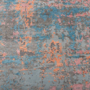K&ouml;nnte beinhalten: Abstrakter Teppich mit einem Used-Design. Der Teppich hat eine graue Basis mit Akzenten in Blau, Orange und Rosa. Das Design hat ein strukturiertes Aussehen und erzeugt einen modernen Look. Ideal f&uuml;r Wohn- oder Schlafzimmer.