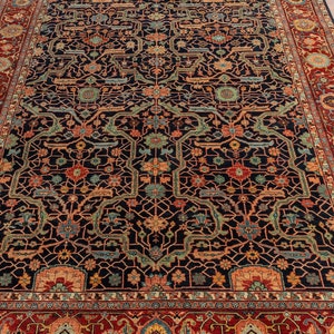 May include: A traditional Persian rug with a dark blue background and intricate floral patterns in shades of red, orange, and green. The rug has a wide border with a repeating design.